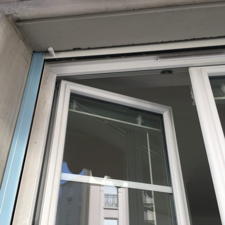 Fenêtre en cours d'installation, avec vue sur un bâtiment à l'extérieur.