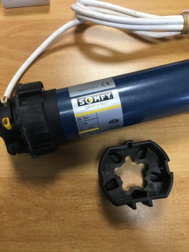 Moteur Somfy Moteur électrique cylindrique bleu avec un dispositif de fixation noir à côté.