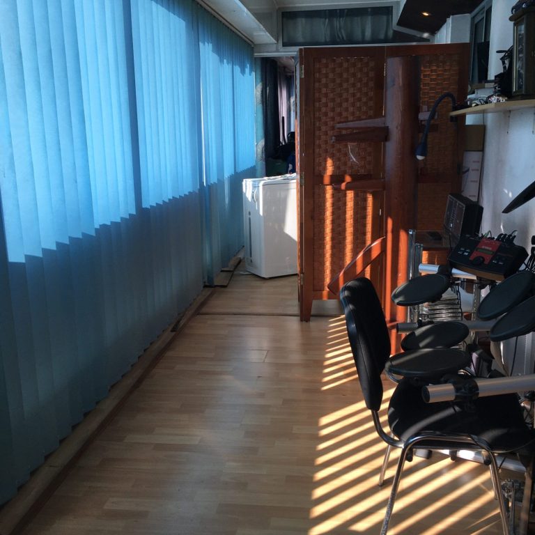 Un couloir avec des fauteuils, des rideaux bleus et des lumières zébrées au sol.