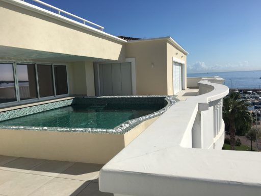 Stores BSO Terrasse avec piscine et vue sur la mer. Ciel dégagé et architecture moderne.