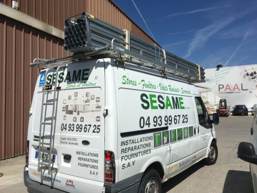 Notre véhicule de transport Camion de service SESAME avec échelle et matériel sur le toit, stationné à l'extérieur.